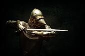 Portrait of a knight in armor, his sword in his hands, performing an attack parade - Stock Image