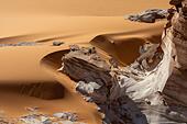 A crumbling white rock formation in the curvy orange sands of the Sahara desert near Ounianga Kébir - Stock Image
